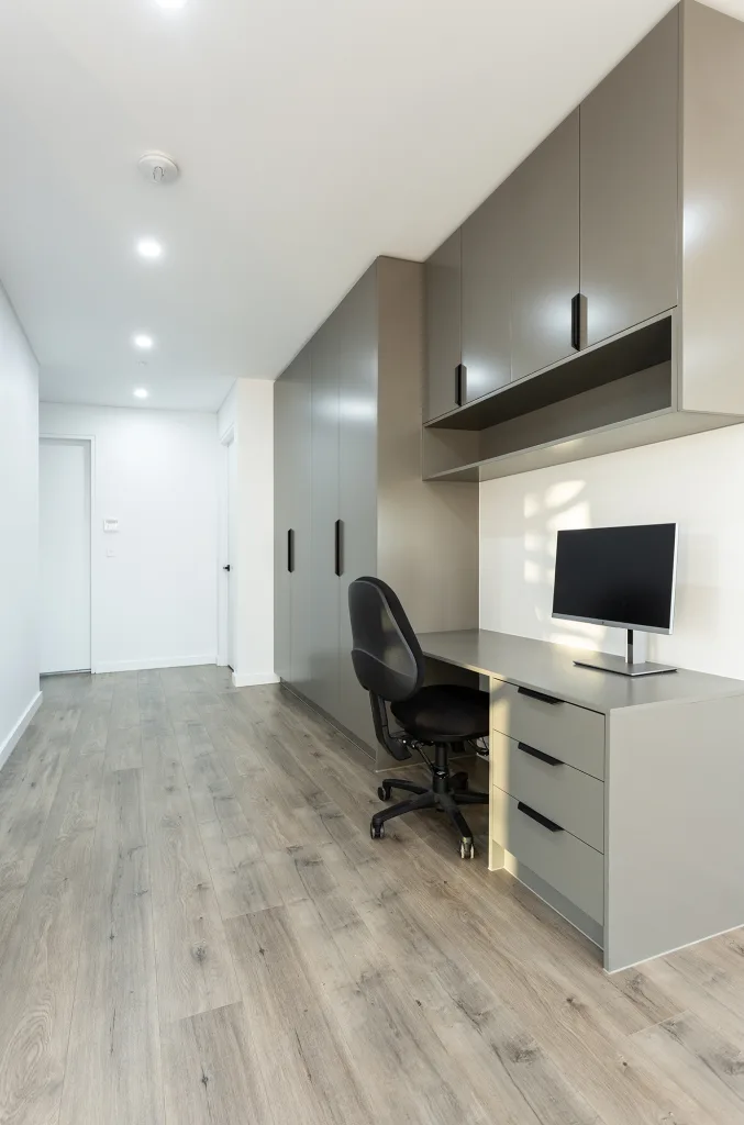 Image shows a spacious office with wooden floors, desk, and computer