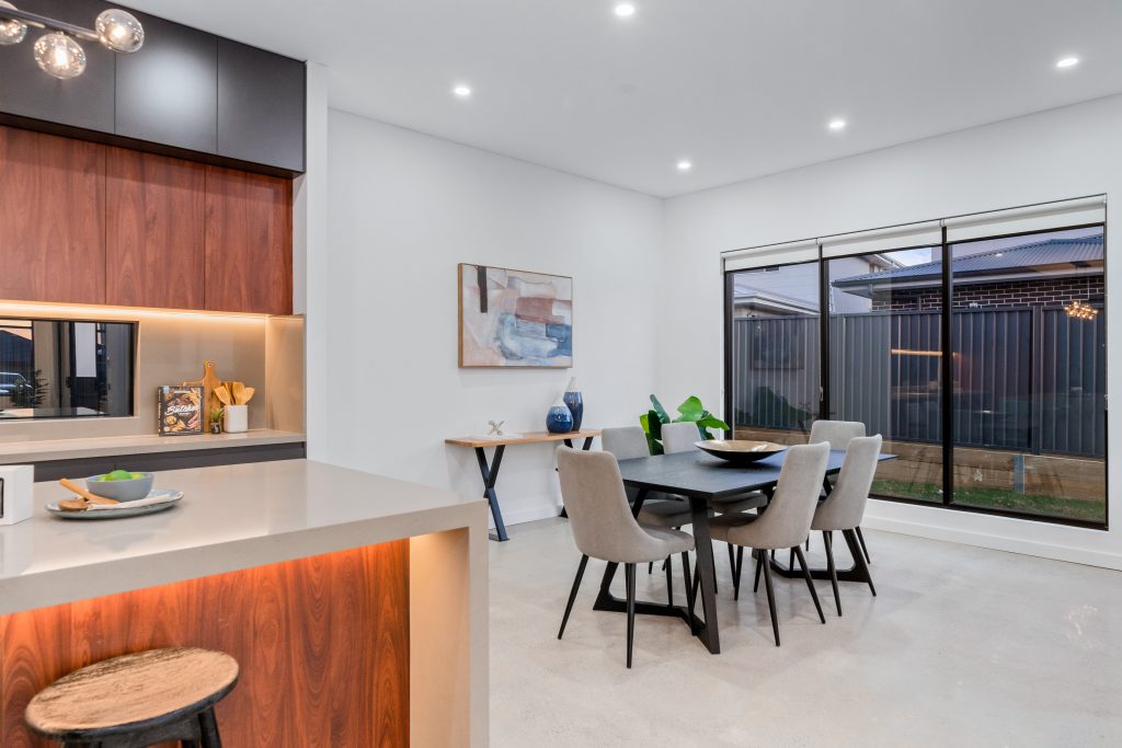 Image shows a modern kitchen and dining area with stone floors and large windows, built and designed by Sydney based home builders Benelong Projects