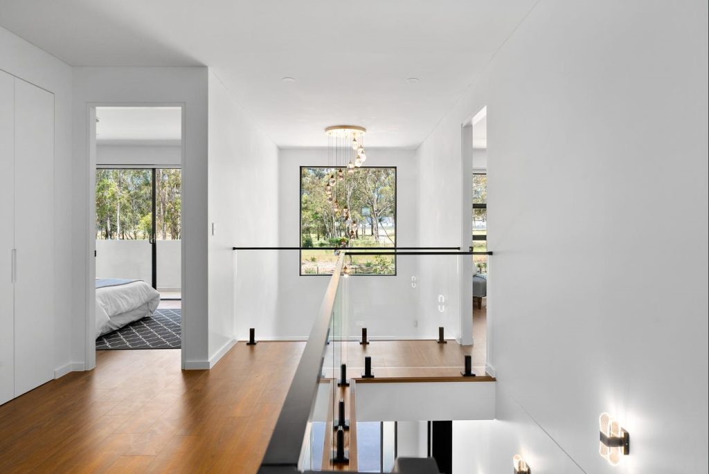 Image shows a well-lit and spacious hall-way with bright natural lighting. Large windows with bright wooden floors