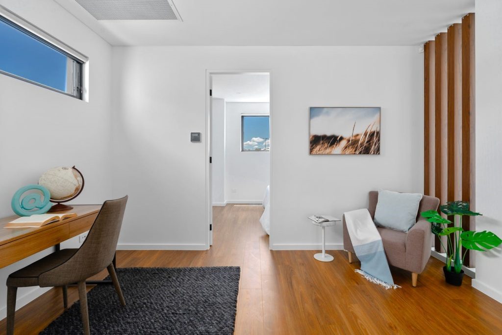 Image shows a study room with wooden floors and desk. Well lit with indoor plants and arm chairs with side tables. Spacious interior design and build by Benelong Projects, Sydney based home builders
