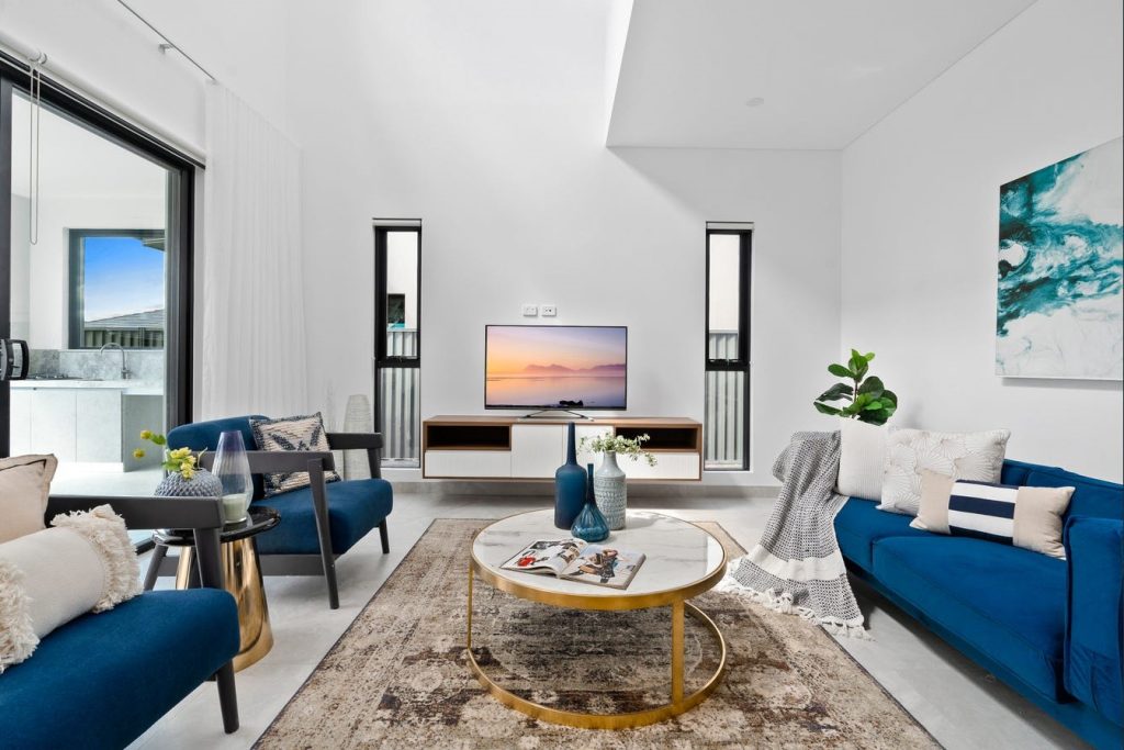Image shows a living / entertaining area with stone tiled floor, white walls and large ranch-slider. Room is well-lit with natural light.