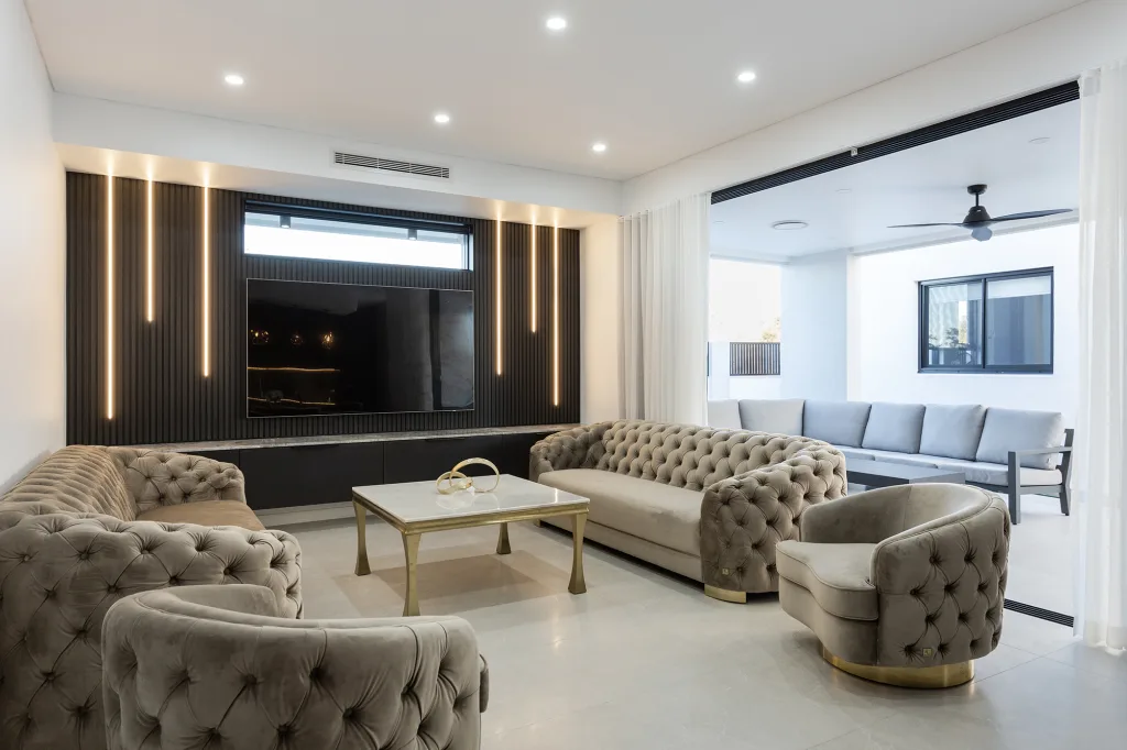 Image shows a spacious living room with large TV and mood lighting