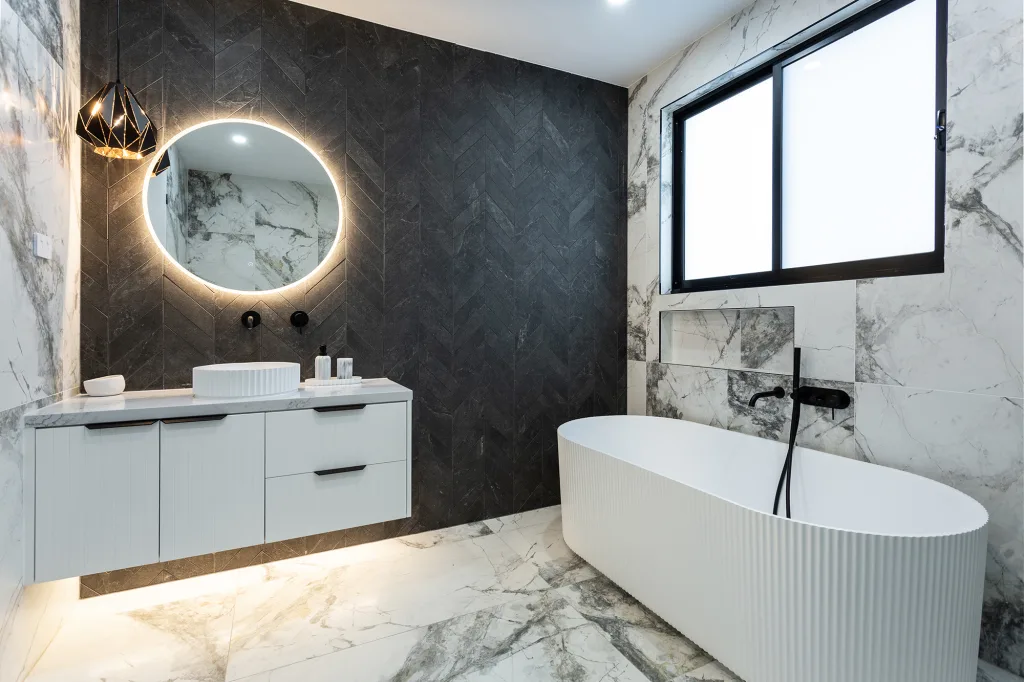 Image shows a bathroom with bath, sink, and white marble floors