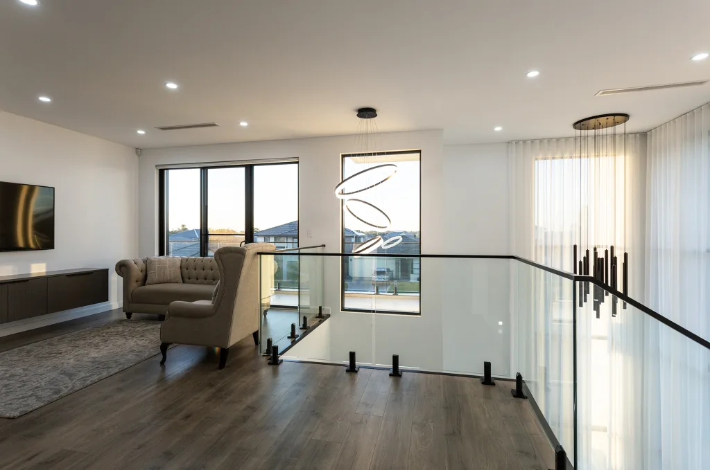 Image shows an upstairs living area with wooden floors and glass barrier