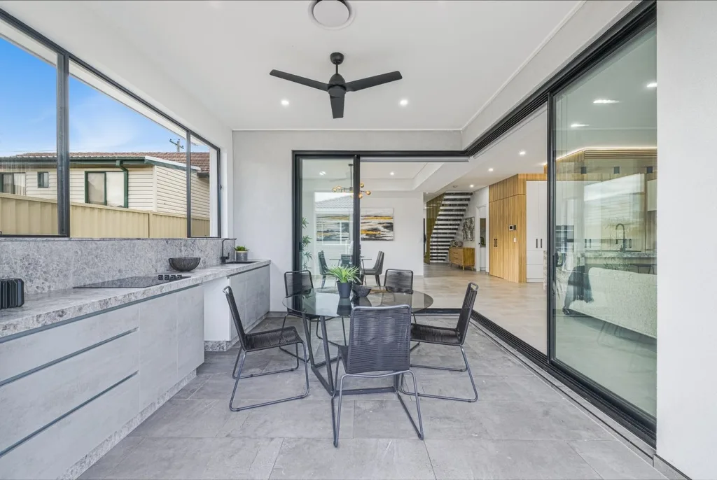 Image shows an entertaining area with large grey tiled floors, granite bench-tops and in-built glass cooker
