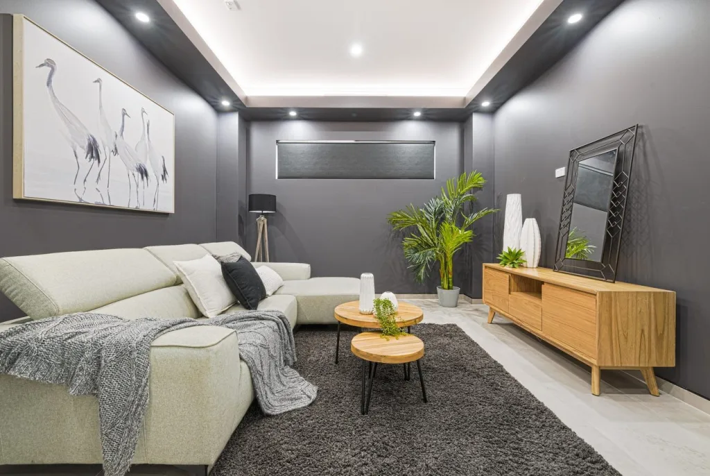 Image shows a comfortable living area with sofas, grey walls, entertainment unit and TV