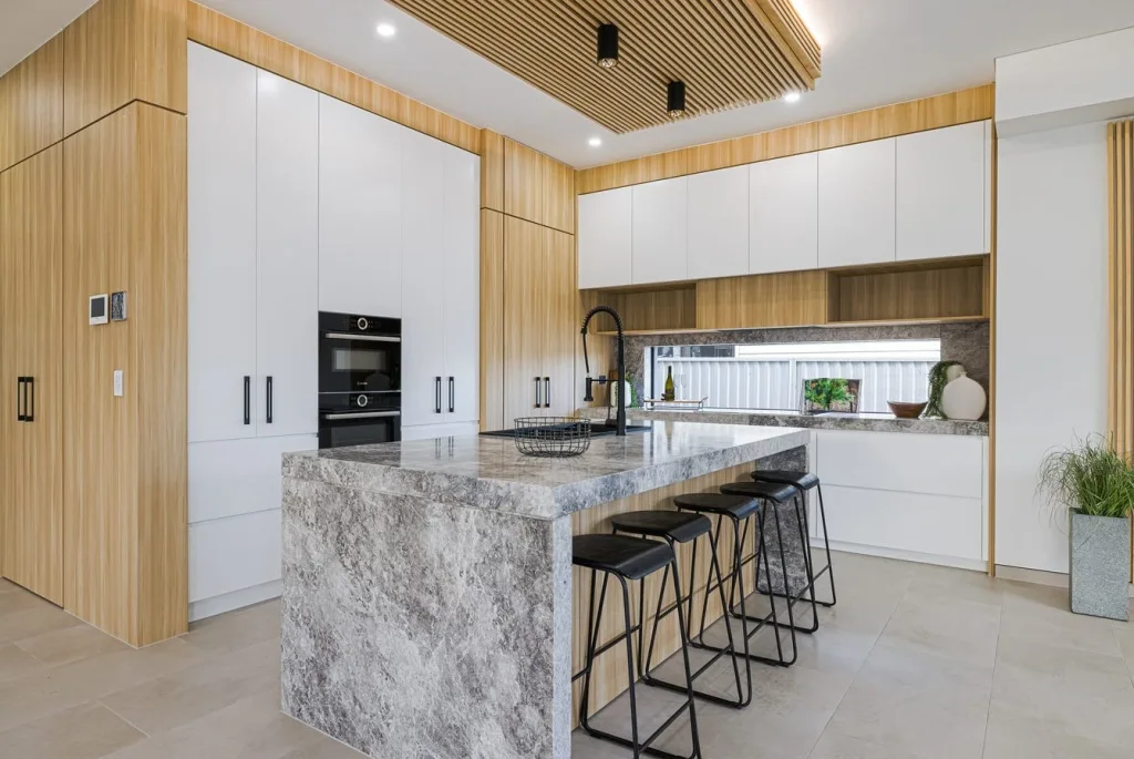Image shows a kitchen with breakfast bar. The Kitchen has stone tile floors and granite bench tops