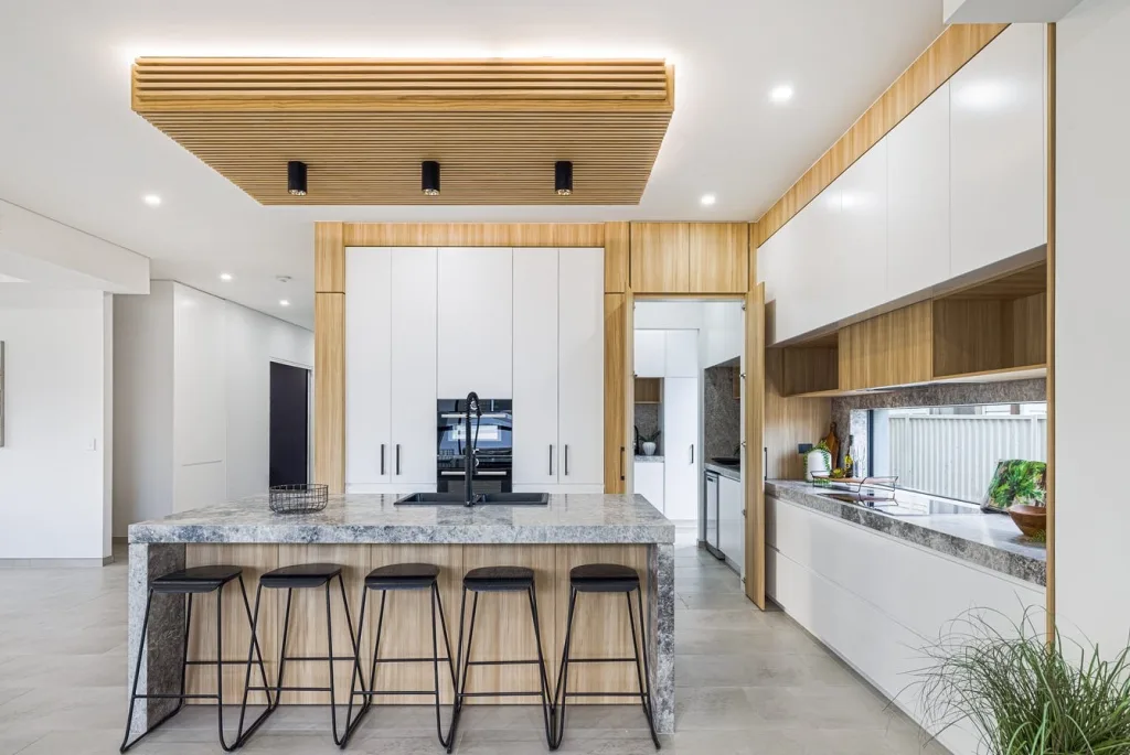 Image shows the kitchen area of a home built by Benelong Projects, Sydney Home builders. The Kitchen has stone tile floors and granite bench tops