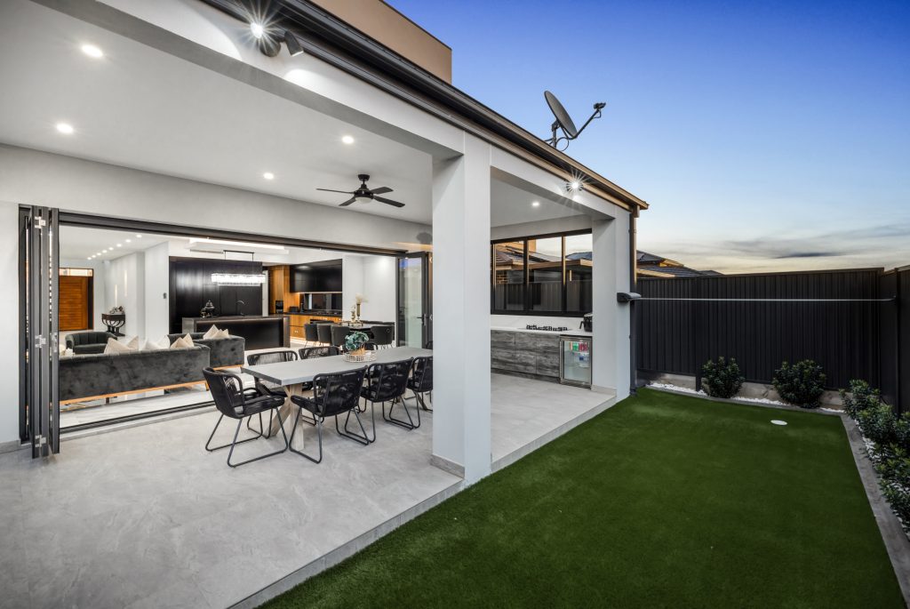 Image shows a Benelong Projects house build with large outdoor living area, with garden with lush green grass and an outdoor table and chair set. Perfect for entertaining, Granite tiled floor. Large ranchslider