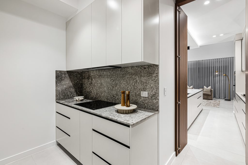 Image shows a second cooking area with granite bench-top and glass top stove. Custom designed and built by Benelong Projects.