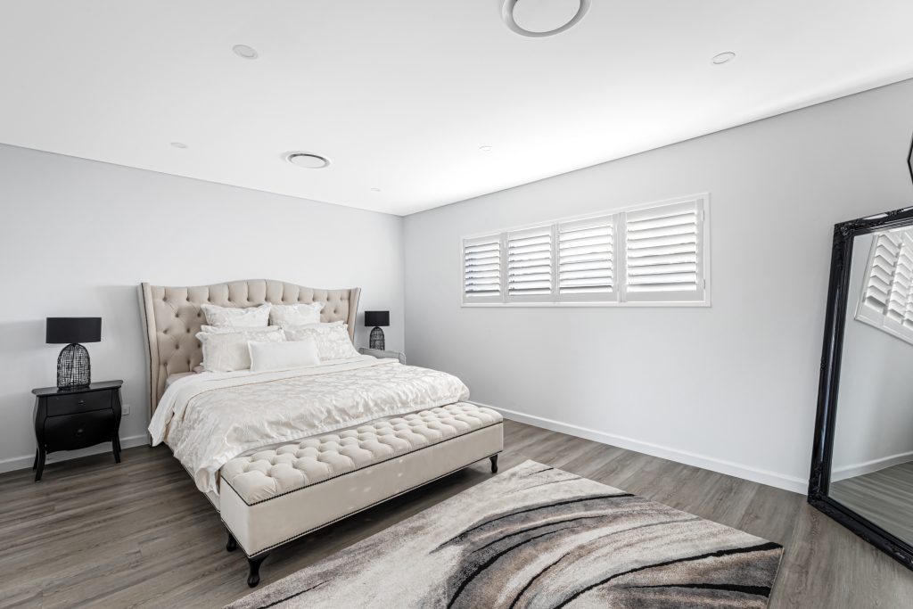 Image shows a Spacious Bedroom with excellent interior design scheme. Large bed, mirrors, wooden flooring, down lighting