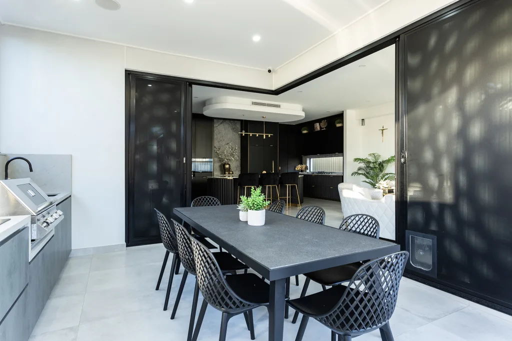 Image shows an outdoor entertainment area with table, chairs, and outdoor gas cooker