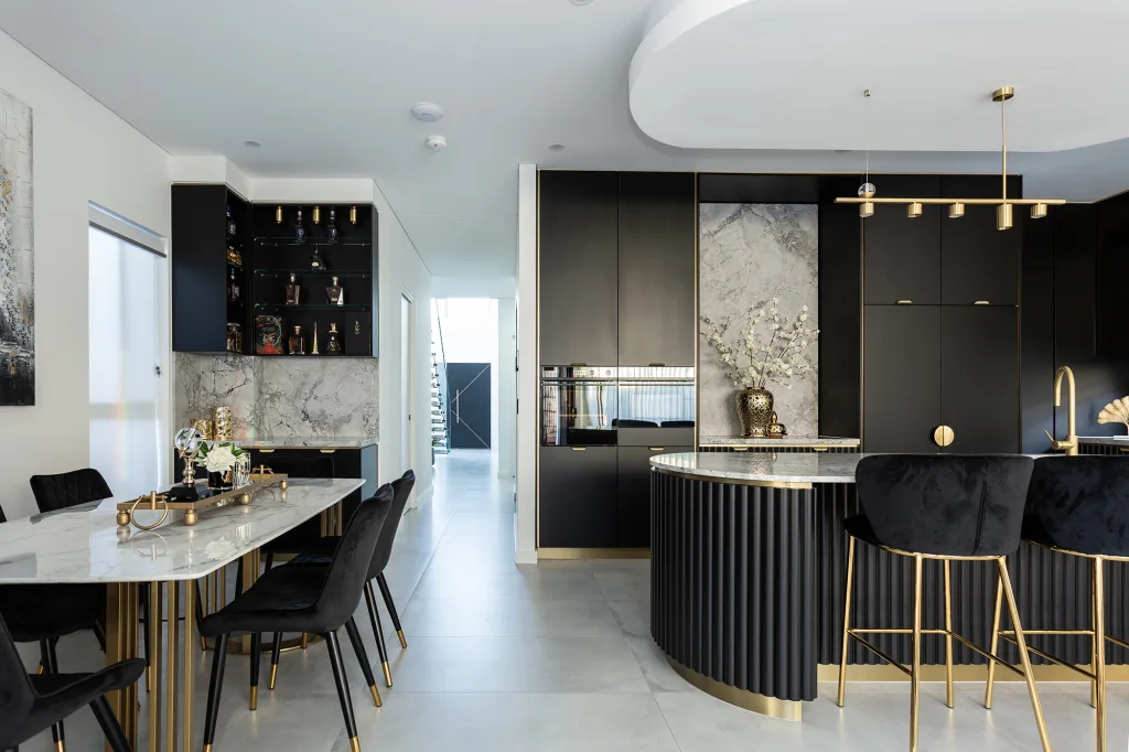 The images shows a kitchen and dining room with grey stone tiled floors and marble walls