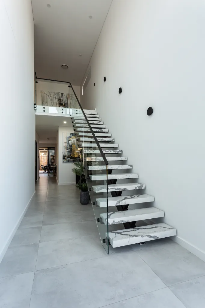 Image shows a spacious entrance way with white granite staircase and grey stone tiled floor