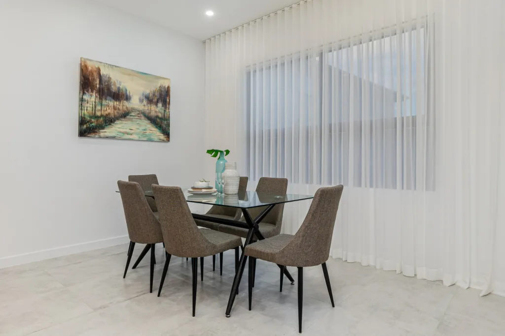 Image shows a spacious dining area with table, chairs, and large windows