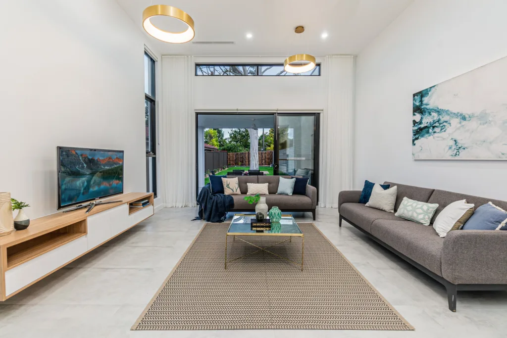 Image shows the living space with white stone tiles, white walls and comfortable couches