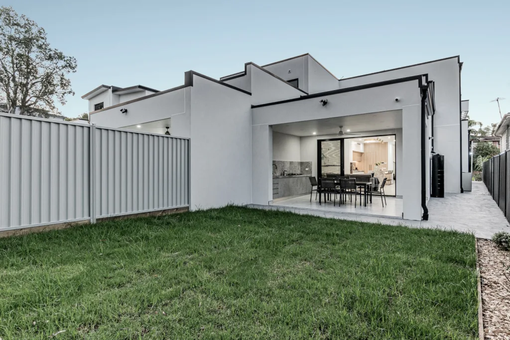Image shows the garden area of a home built by Sydney home builders Benelong Projects. The yard is spacious with green grass and an outdoor entertaining area